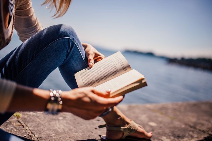 A woman reading a magazine at the beach. 