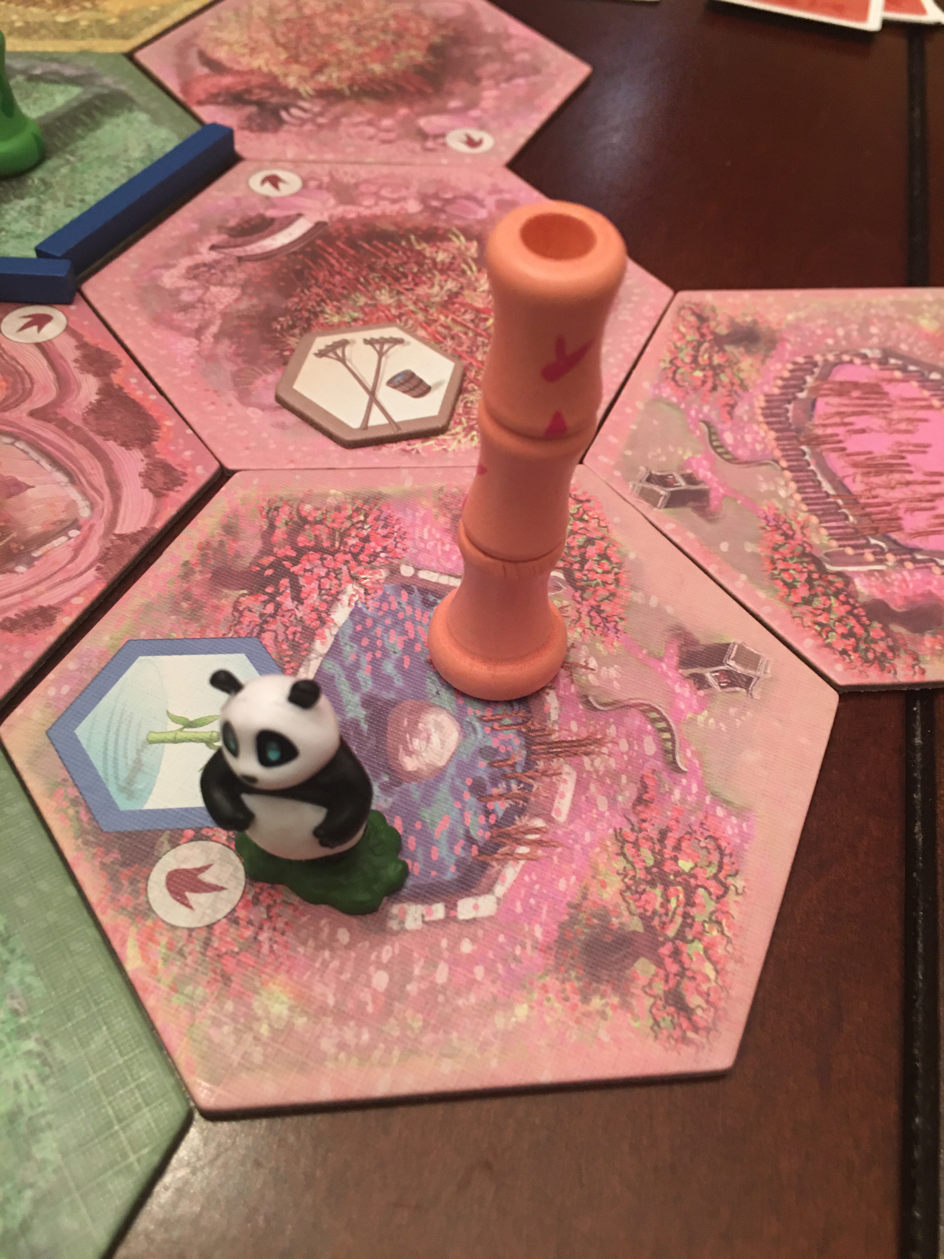 Panda figurine on tiles with pink bamboo pieces. 