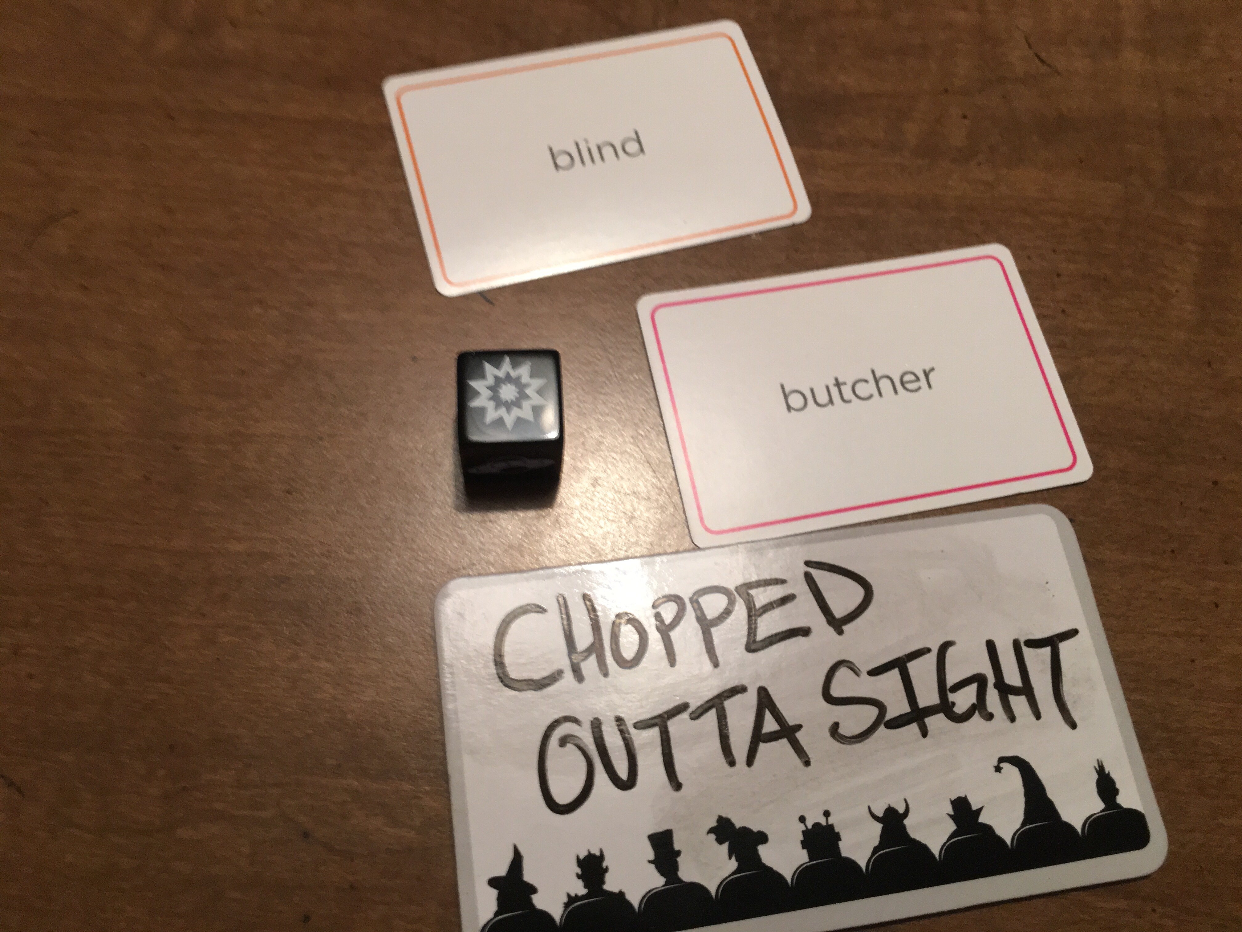 Image Description: the starburst action die with the cards Blind + Butcher. The whiteboard says, Chopped: Outta Sight. 