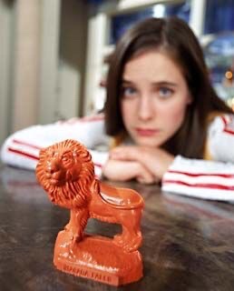 Image: Jay from Wonderfalls in background, with a souvenir wax lion in the foreground. 